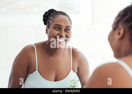 Smiling african woman looking at son reflet dans un miroir Banque D'Images