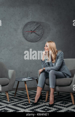 Thoughtful young businesswoman sitting on armchair en salle d'attente au bureau moderne Banque D'Images