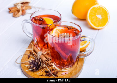 Vin chaud, boisson d'hiver chaud avec des baies, l'orange, les épices, la cannelle dans verre tasses sur la table en bois blanc avec des ingrédients et des épices. foc sélective Banque D'Images