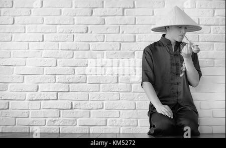 Novice asiatique sur un mur en brique blanche Banque D'Images