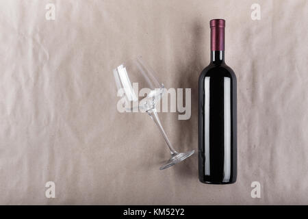 Set de vin - une bouteille de vin rouge avec un verre vide sur un fond gris Banque D'Images