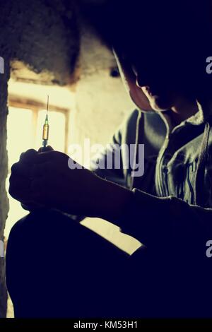 Concept de médicaments. concept de maladie. toxicomane homme avec l'aide de seringues médicaments.thème sombre, jeune homme très stressé, il aurait la toxicomanie. Banque D'Images