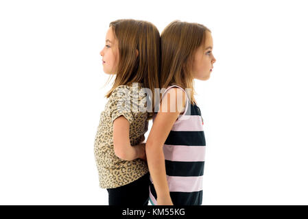 Les filles sont jumeaux identiques se tourna face à dos à dos. concept de la famille et l'amour fraternels. profil Vue latérale des sœurs de jouer, sourire et rire. Banque D'Images