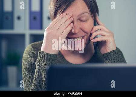 Fatigué épuisé femme freelancer talking on mobile phone à partir de son propre bureau à domicile d'affaires de démarrage Banque D'Images