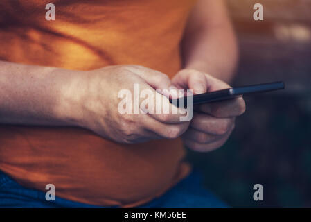 Pregnant woman texting outdoors on park bench, adulte femelle de race blanche à l'aide de téléphone mobile pendant la grossesse Banque D'Images