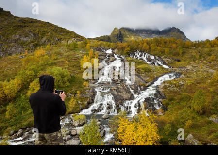 Photographie touristique cascade lofoten avec un téléphone mobile en Norvège Banque D'Images