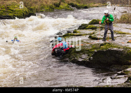 Les kayakistes de l'eau blanc pratiquer les techniques de sauvetage avec un jet direct dans la queue des serpents sur la rivière Dee dans le Nord du Pays de Galles Banque D'Images