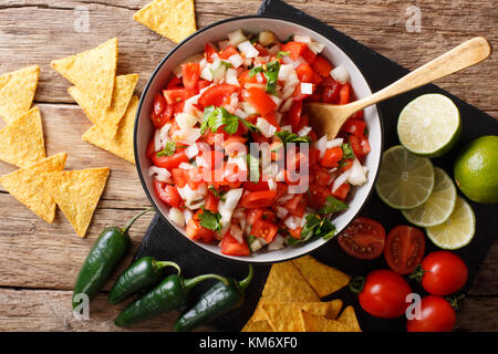 Pico de Gallo épicé fait maison close-up dans un bol et des nachos sur la table supérieure horizontale. Vue de dessus Banque D'Images