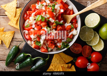 Pico de Gallo mexicain à partir de tomates, oignons, coriandre et piment jalapeno close-up dans un bol et des nachos sur une table horizontale. haut Vue de dessus Banque D'Images