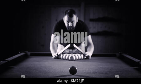 Un homme avec une barbe joue un grand billard. Partie dans une piscine de 12 pieds Banque D'Images