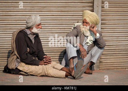 Deux hommes sikh punjabi avec barbe blanche et turban assis à parler dans la rue, à Amritsar, Punjab Banque D'Images