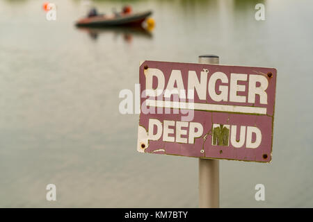 Signer : Danger, boue profonde, avec un bateau dans l'arrière-plan flou, vu à Topsham, Devon, UK Banque D'Images