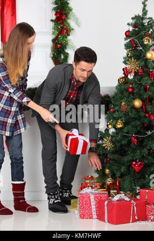 Heureux parents ont mis des cadeaux de Noël pour les enfants de moins de un arbre décoré Banque D'Images