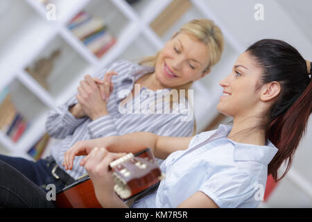 Aider l'enseignant élève à jouer de la guitare en leçon de musique Banque D'Images