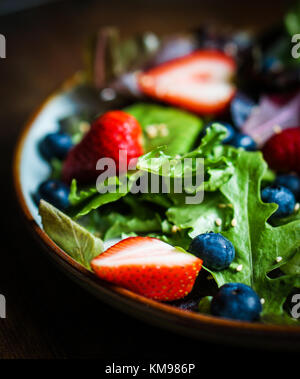 Salade verte aux fruits rouges sur fond de bois Banque D'Images