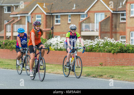 Les femmes la bicyclette en donnant des signes de la main avant de tourner sur une route dans le Royaume-Uni. Banque D'Images