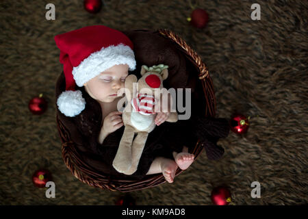 Mignon bébé de trois mois avec bear hat dans un panier, dormir, décoration de Noël autour de lui Banque D'Images