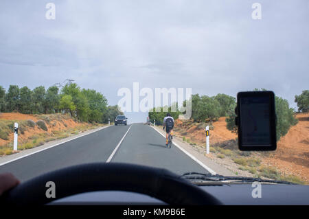 Conduire lentement derrière un cycliste par route locale plus de ligne continue. Vue depuis l'intérieur de la voiture Banque D'Images