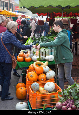 Une femme achète des légumes dans un étal avec des caisses de citrouilles et de courges sur le marché primé des agriculteurs de Stroud, Gloucestershire, Royaume-Uni Banque D'Images