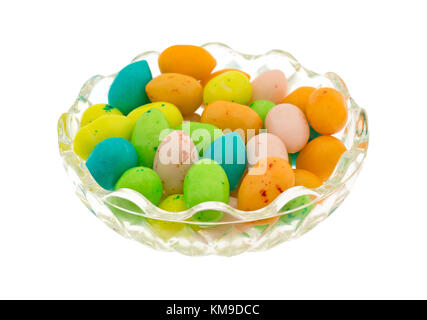 Un petit bol en verre rempli d'oeufs de Pâques colorés candy bubble gum isolé sur un fond blanc. Banque D'Images