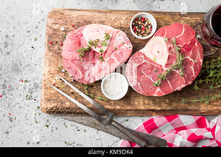 Tranches de jarret de veau fraîche Viande de boeuf pour osso buco la cuisson sur une planche à découper avec des ingrédients et assaisonnements le thym, poivre, sel. Banque D'Images