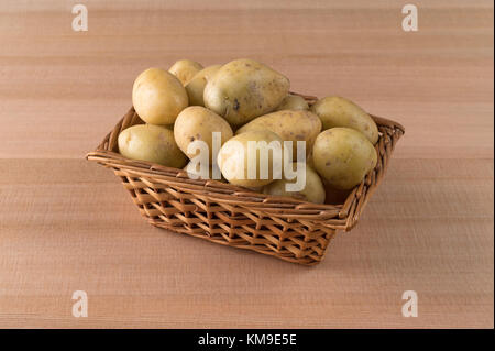 Un petit panier en osier rempli de pommes d'or sur un cèdre comptoir. Banque D'Images