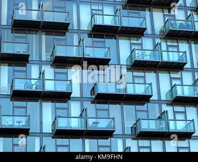 Motif créé par grille d'un balcon pourvu de sièges et des vélos sur la façade vitrée bleue du nouveau bâtiment à Salford Quays, Manchester, UK Banque D'Images