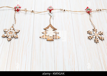 Jouets en bois Noël sous la forme d'un arbre de Noël et des flocons de peser sur une corde sur un fond de bois blanc. Belle carte de vœux festifs wit Banque D'Images