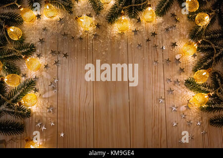 Noël arrière-plan avec une guirlande lumineuse blanche sur table en bois avec les branches de l'arbre de Noël, des étoiles et de la neige. maison de vacances idée pour l'hiver po Banque D'Images