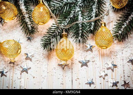 Noël arrière-plan avec une guirlande lumineuse blanche sur table en bois avec les branches de l'arbre de Noël, des étoiles et de la neige. maison de vacances idée pour l'hiver po Banque D'Images