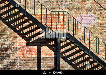 Abstract image montrant un escalier métallique et de l'ombre contre un mur de briques. Banque D'Images