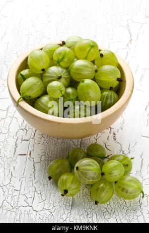 Tas de mûres, récoltées en vert frais fruits Groseille à bol en bois sur fond de table blanc Banque D'Images