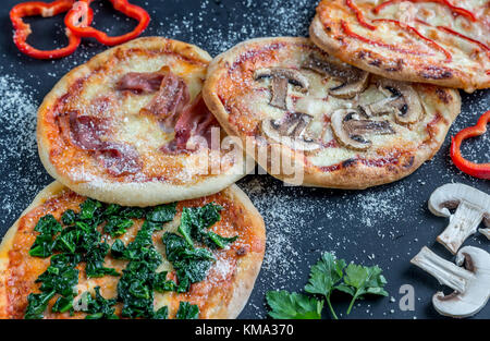 Mini pizzas divers nappages sur la planche de bois Banque D'Images