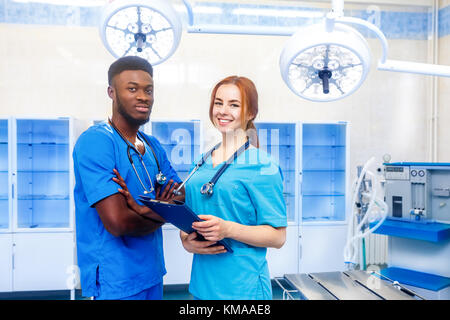 De l'équipe multiraciale de deux jeunes médecins dans un hôpital debout dans une chambre d'exploitation Banque D'Images
