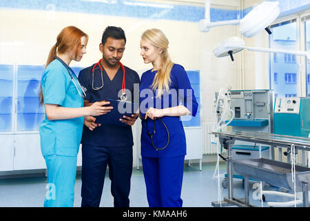De l'équipe multiraciale doctors discussing un patient debout dans une chambre d'exploitation Banque D'Images