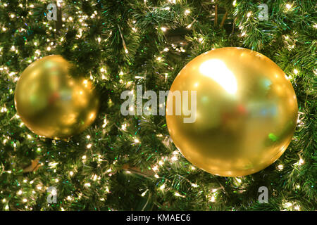 Paire d'ornements de Noël boule brillante d'or sur l'arbre de Noël étincelante, arrière-plan flou Banque D'Images