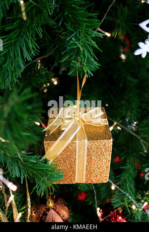 De minuscules paillettes or boîte-cadeau avec ruban d'arc christmas ornament hanging sur l'arbre de Noël Banque D'Images