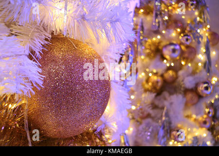 Rose fermée-gold glitter ball shaped christmas ornament avec mousseux floue arbre de Noël en arrière-plan Banque D'Images