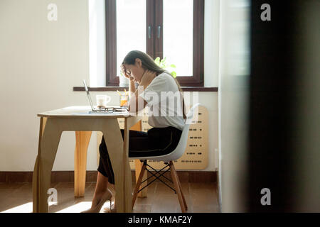 Femme épuisée surchargée de travail voulant dormir et assise sur le lieu de travail, tenant la tête. Manager féminin souffrant de maux de tête et de dépression Banque D'Images
