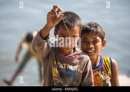 Deux enfants jouant baim(l) l'anguille poisson bébé à côté d'une rivière en burigonga ville de Dhaka. Banque D'Images