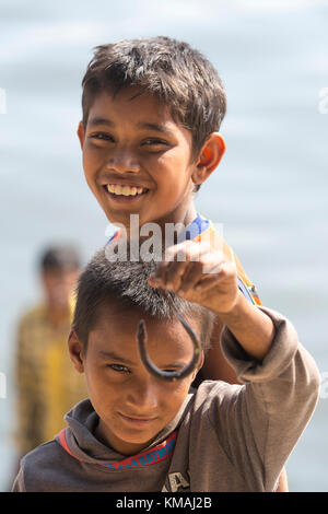 Deux enfants jouant baim(l) l'anguille poisson bébé à côté d'une rivière en burigonga ville de Dhaka. Banque D'Images