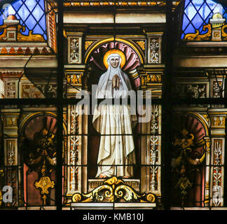 Vitrail représentant un saint en prière dans un habit blanc, dans la cathédrale de Gand, Belgique. Banque D'Images