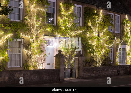 Lumière de Noël décorations sur la façade d'une maison à wisteria plantes dans Broadway à la nuit. Broadway, Cotswolds, Worcestershire, Angleterre. Banque D'Images