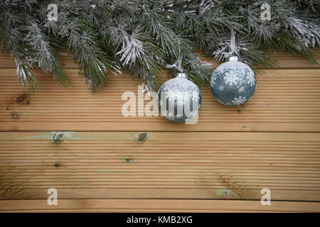 Arbre de Noël de la saison d'hiver avec la neige et garland avec fond en bois naturel rustique et de suspendre des décorations de couleur gris argent baubles Banque D'Images