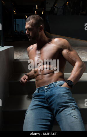 Jeune homme sain Permanent Standing Strong sur les escaliers et Flexing Muscles - Remise en forme musculaire Bodybuilder Athletic Model Posing après exercices - une Plac Banque D'Images