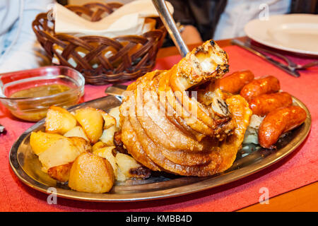 Jarret de porc rôti avec pommes de terre frites et saucisses en métal plaque Banque D'Images