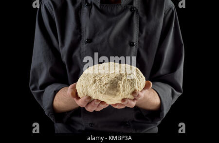 Male hands holding pâte isolé sur fond sombre. Banque D'Images