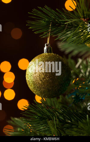 Gros plan d'une boule dorée scintillante suspendue dans le sapin de noël Banque D'Images