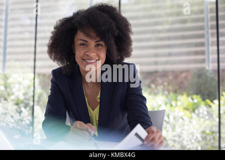 Portrait une femme d'affaires souriante et confiante qui passe en revue les documents administratifs Banque D'Images