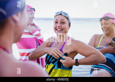 Les femmes souriantes nageurs d'eau libre s'assèchent avec des serviettes plage Banque D'Images